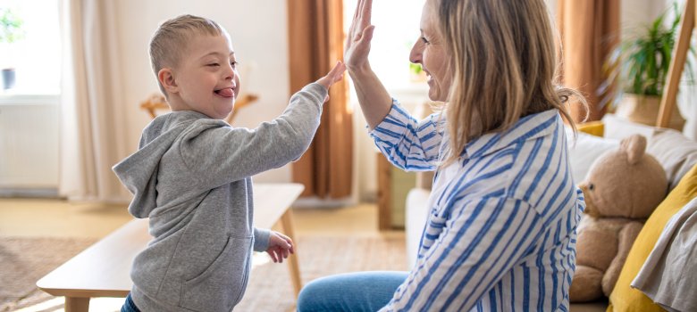 Single mother playing with down syndrome child at home.