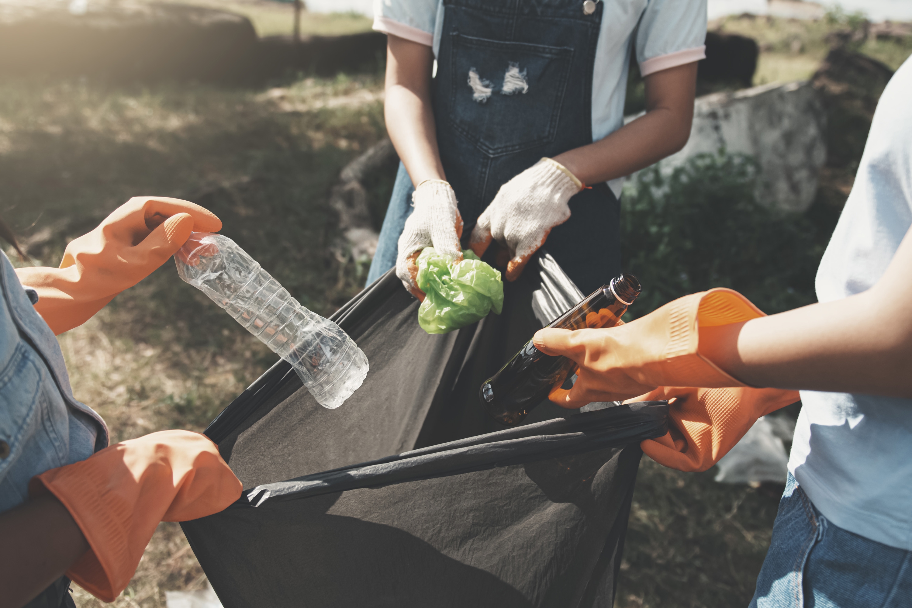 people picking up garbage and putting it in plastic black bag fo