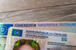 German ID card and driver’s license in hand, EU flag, Modern European driving permit, identification and travel, personal card and license, EU citizen travel, mobility documents