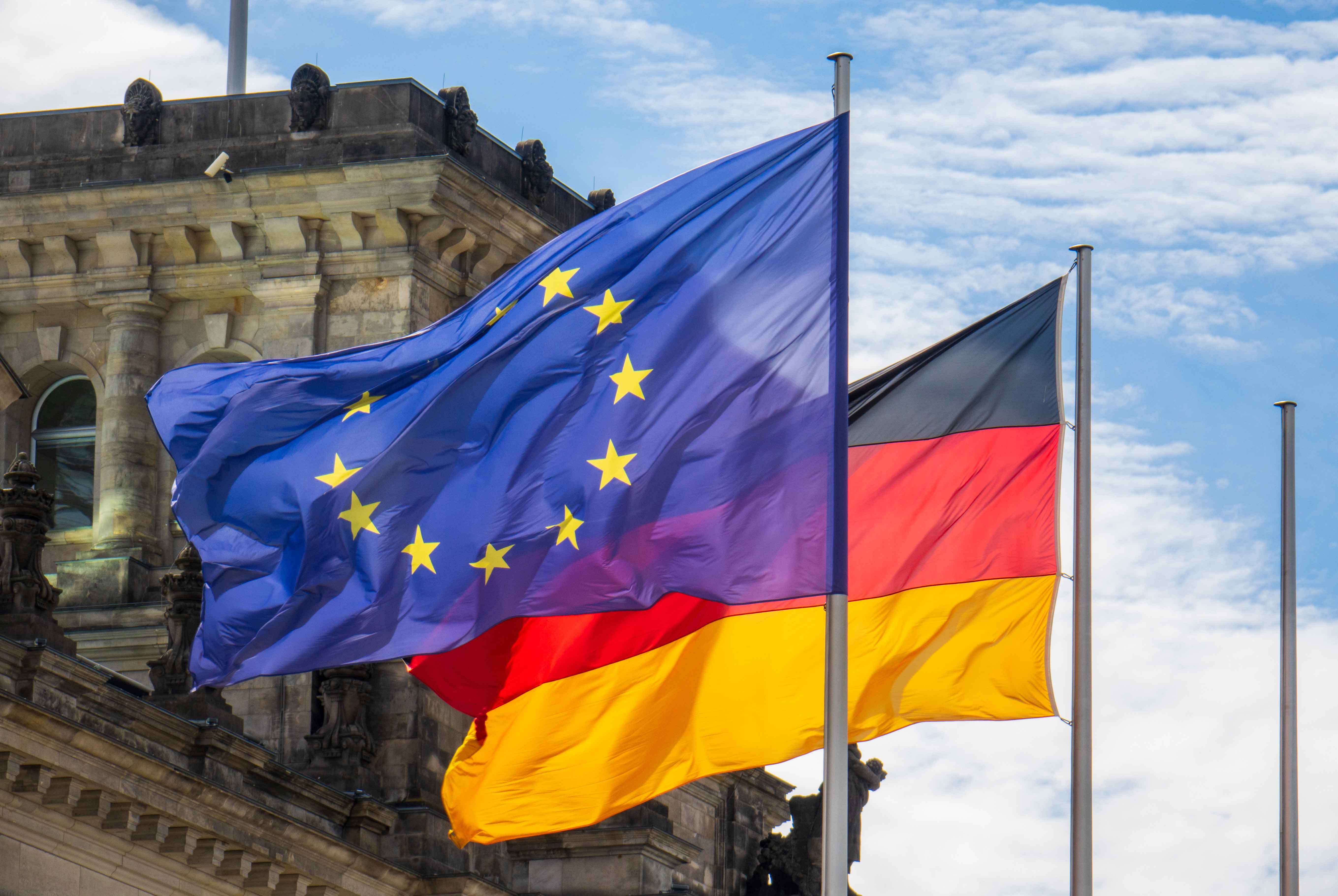 Flaggen von Deutschland und der Europäischen Union wehen im Wind vor dem Reichstag in Berlin.