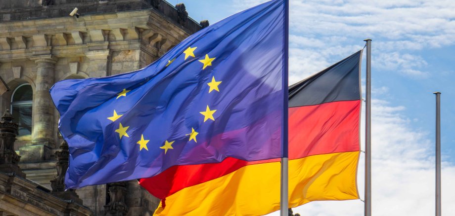 Flaggen von Deutschland und der Europäischen Union wehen im Wind vor dem Reichstag in Berlin.