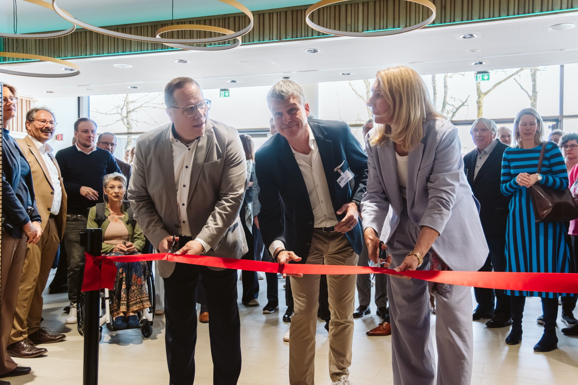 Stadtbaurat, Projektleiter und Bürgermeisterin durchschneiden das rote Band zur neuen Halle