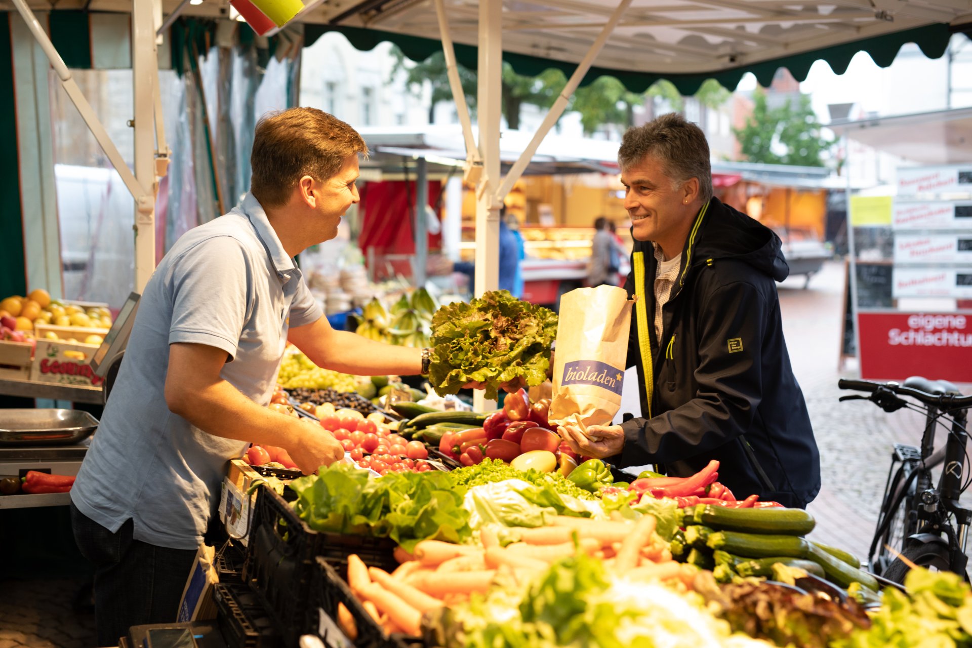 Obsthändler übergibt Ware an Kunden auf Wochenmarkt