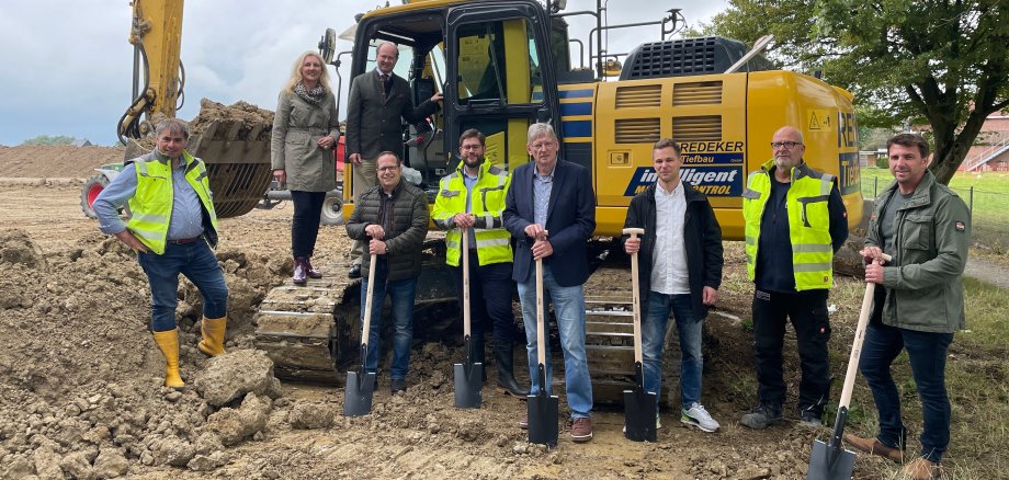 Gruppe Arbeiter vor einem großen gelben Bagger