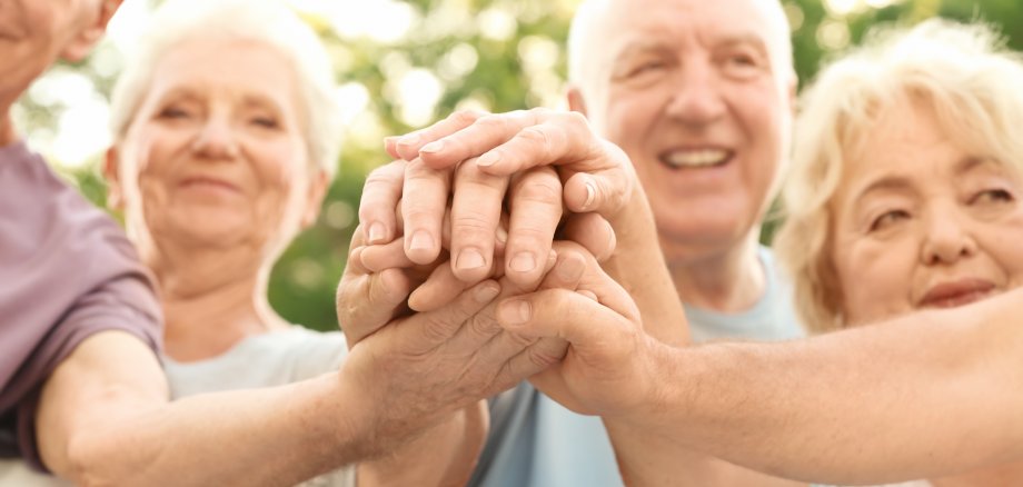 Gruppe älterer Menschen legt die Hände aufeinander als Zeichen der Einheit Gruppe älterer Menschen legt die Hände aufeinander als Zeichen der Einheit