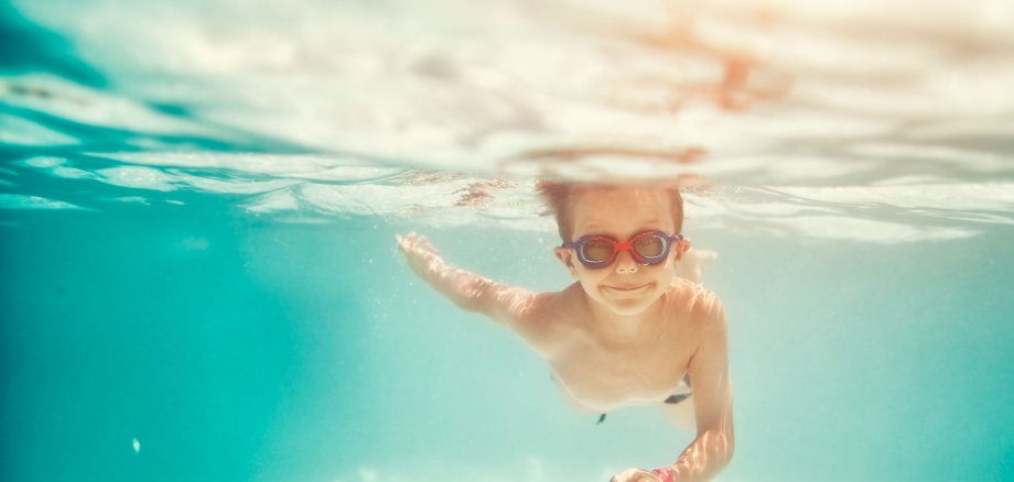 Kind schwimmt im Hallenbad