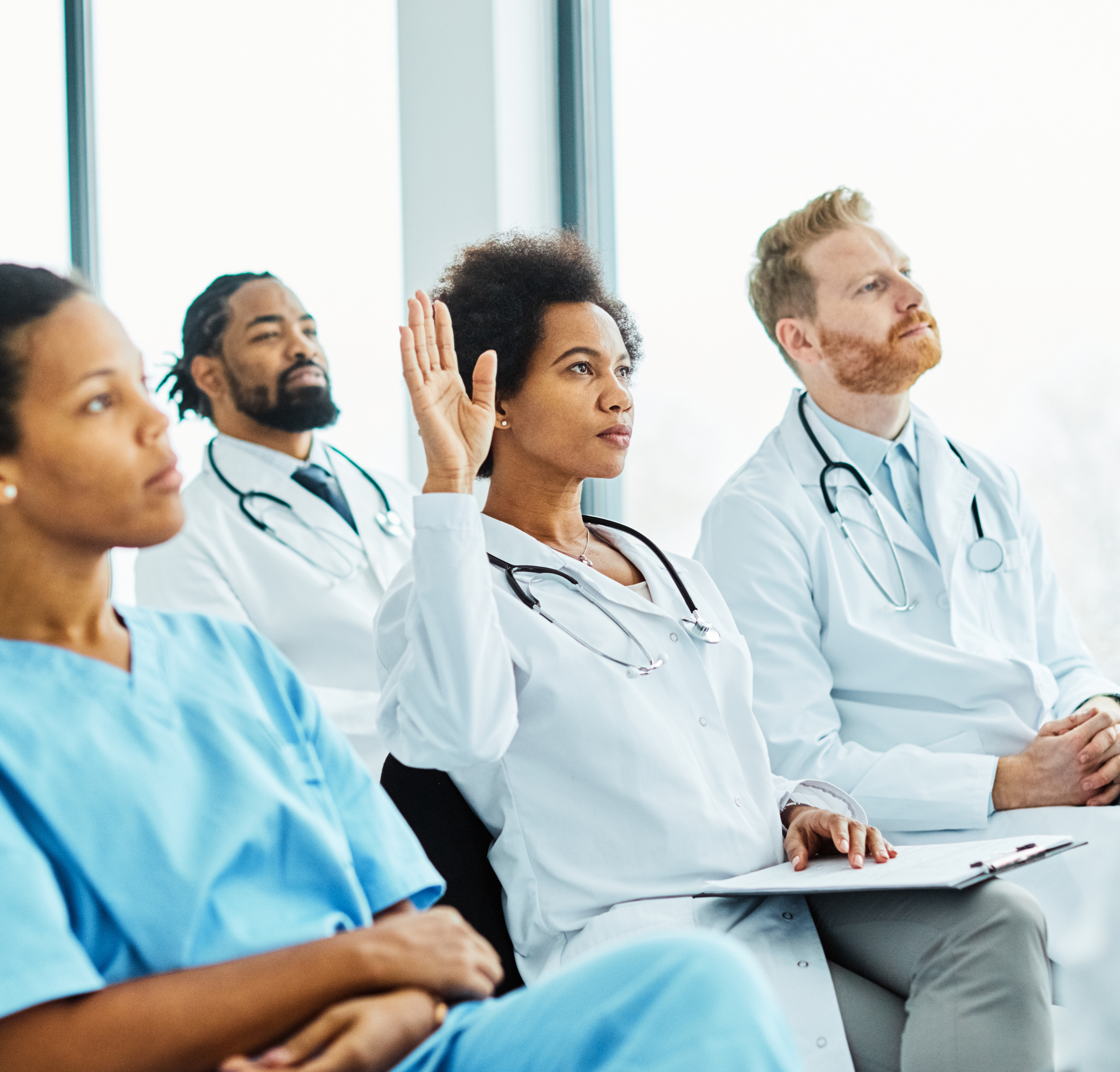 Mehrere Ärzt:innen sitzen in der Zuhörerschaft auf einem Seminar Mehrere Ärzt:innen sitzen in der Zuhörerschaft auf einem Seminar