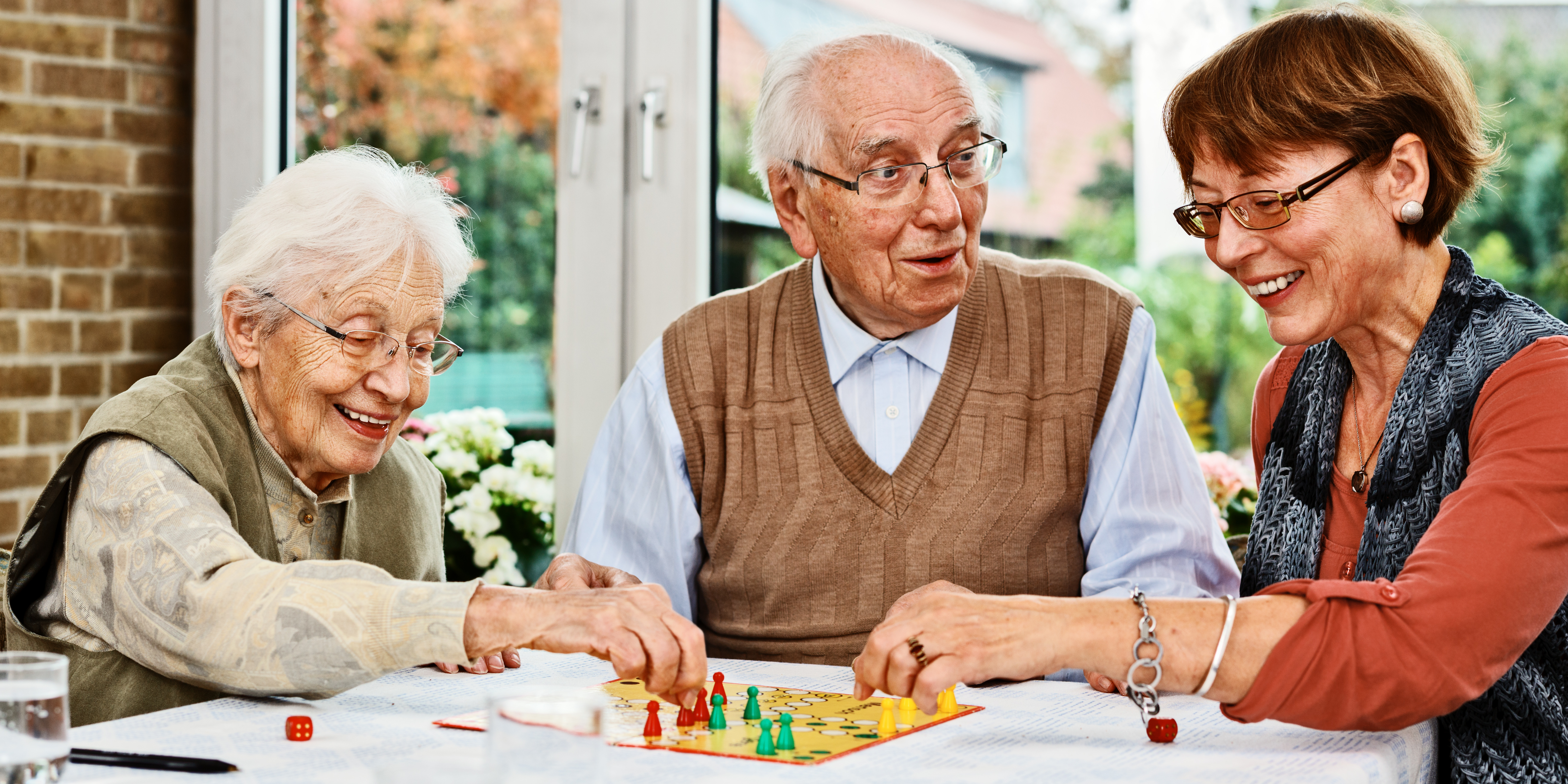 Älteres Ehepaar und Tochter spielen ein Brettspiel