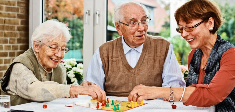 Älteres Ehepaar und Tochter spielen ein Brettspiel