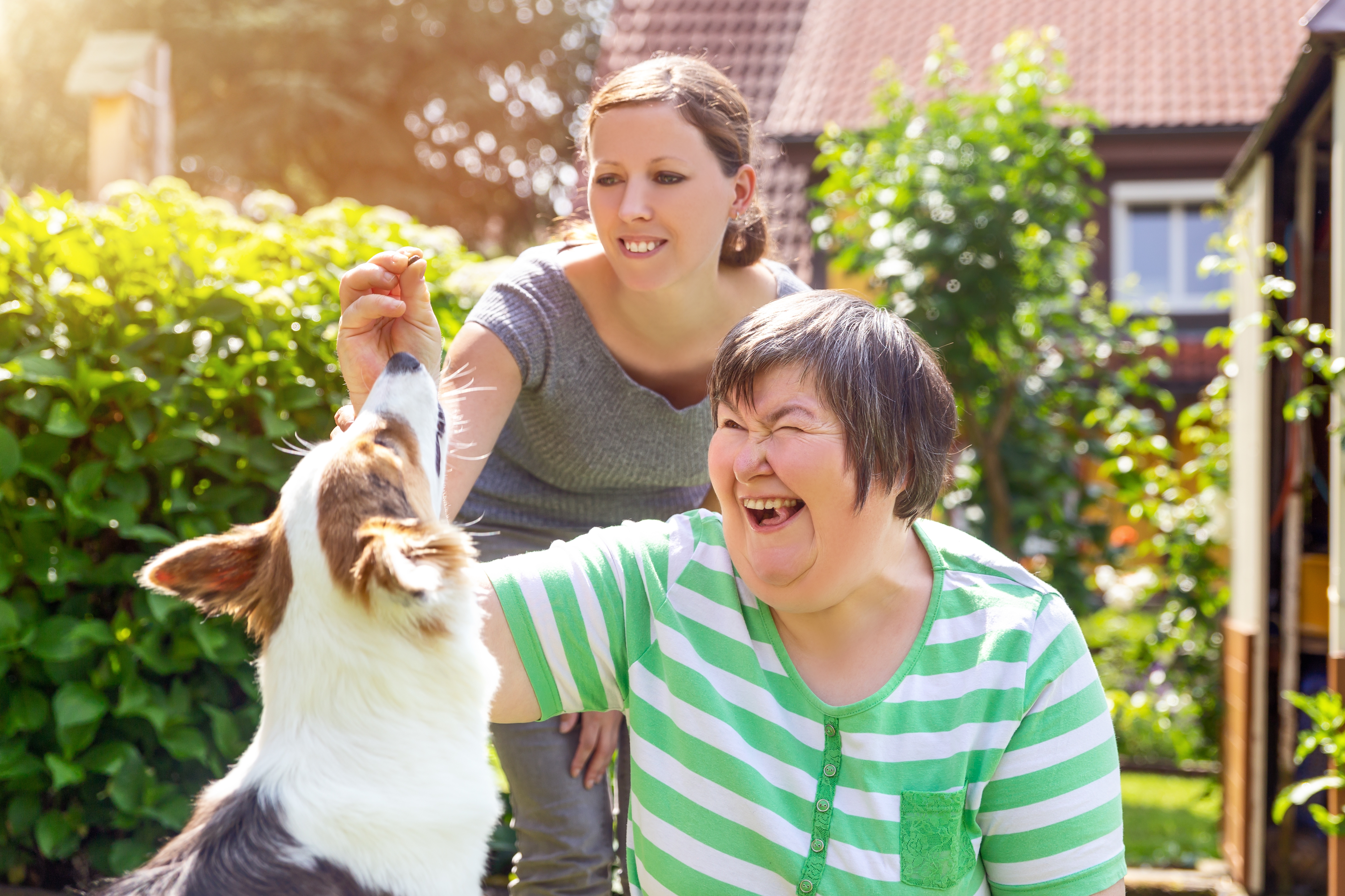 Alternativetherapie mit einem Hund, geistig behinderte Frau und Therapeutin im Garten