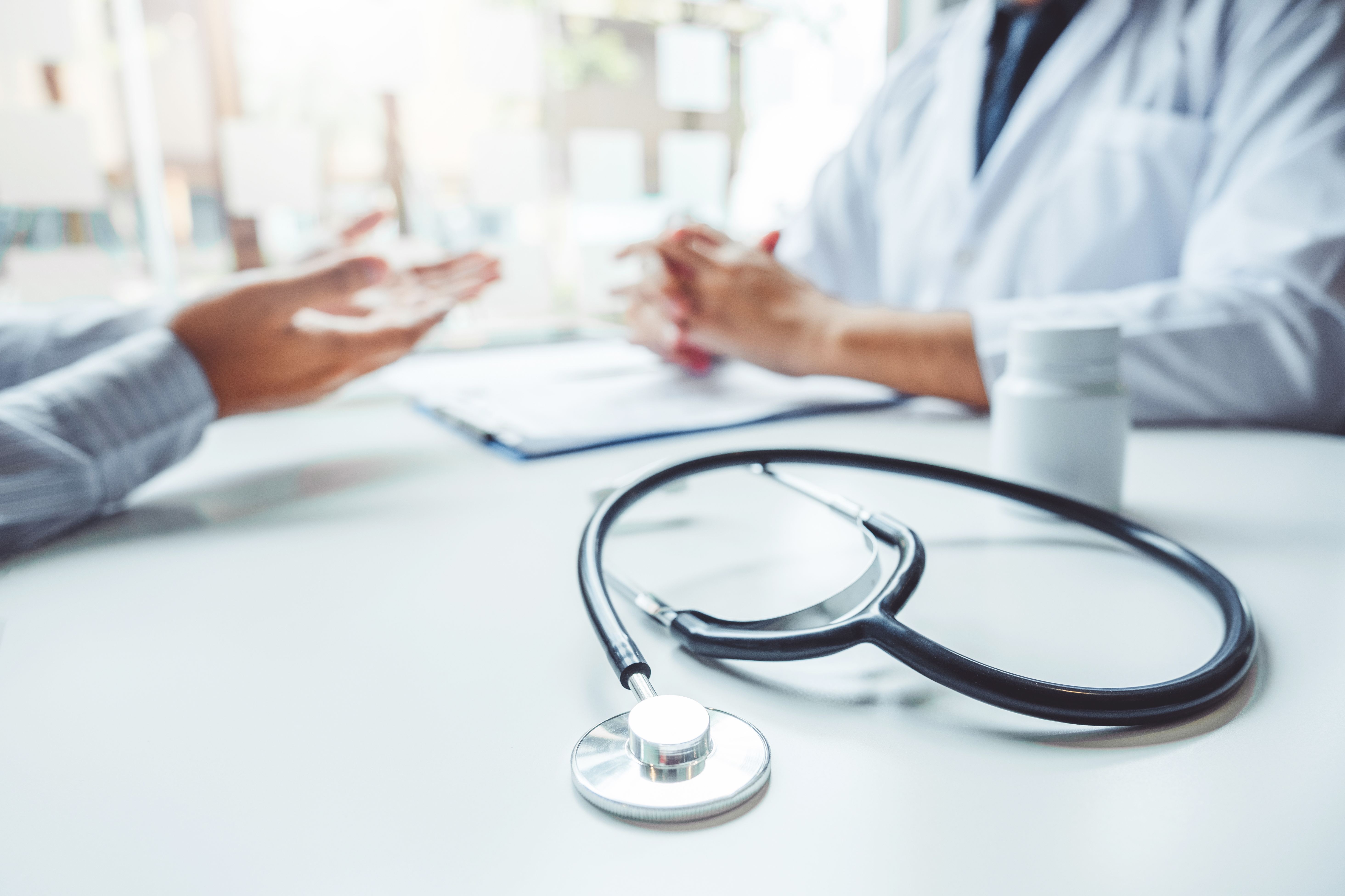Doctors and patients consulting and diagnostic examining sit and talk. At the table near the window in the hospital medicine concept