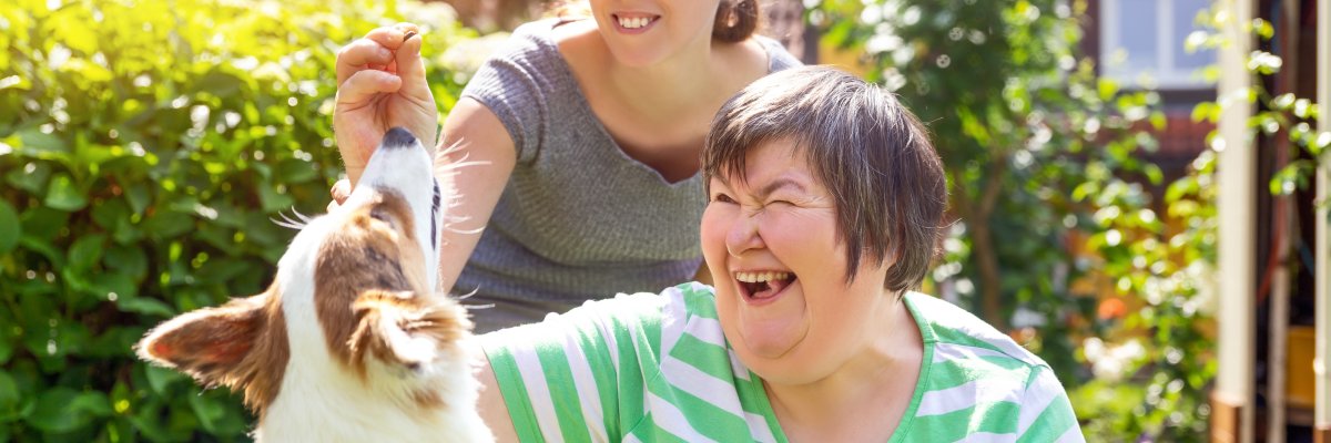 Alternativetherapie mit einem Hund, geistig behinderte Frau und Therapeutin im Garten