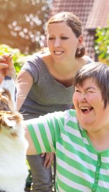 Alternativetherapie mit einem Hund, geistig behinderte Frau und Therapeutin im Garten