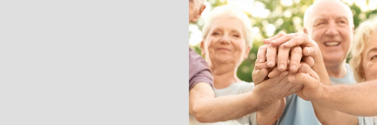 Group of elderly people putting hands together as symbol of unit