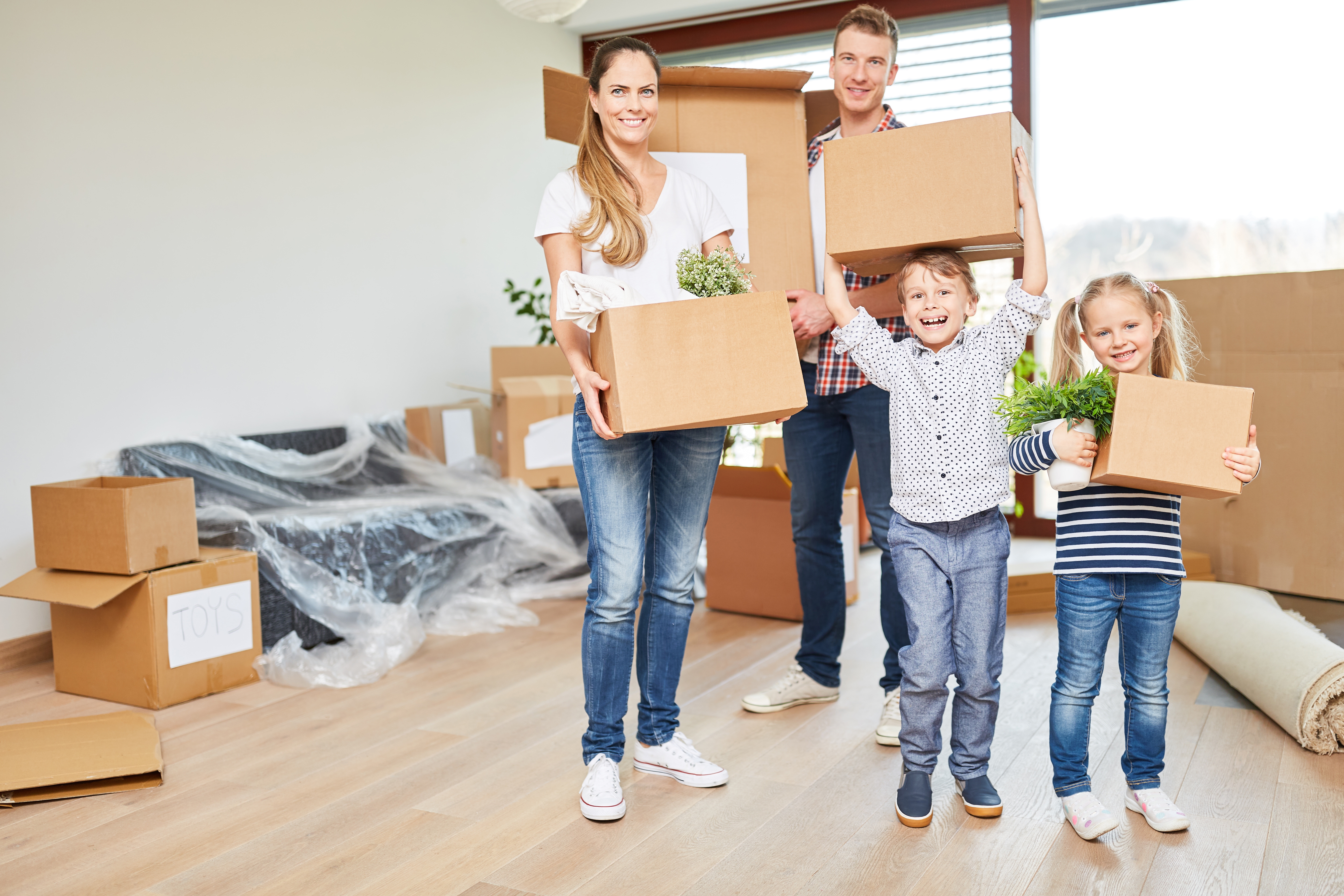 Eltern und Kinder tragen Umzugskartons