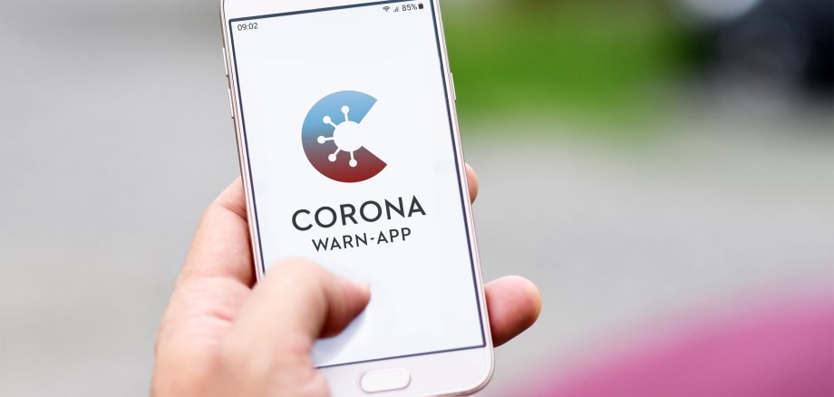 Germany - June 2020: Official German Corona Warning App on mobile phone held by hand on blurry background