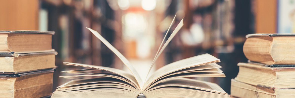Book in library with old open textbook, stack piles of literatur Book in library with old open textbook, stack piles of literatur