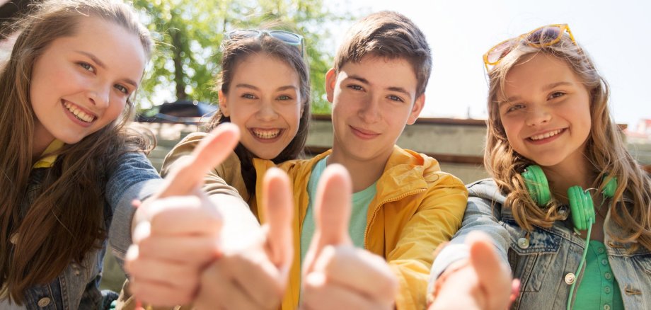 teenage friends or students showing thumbs up