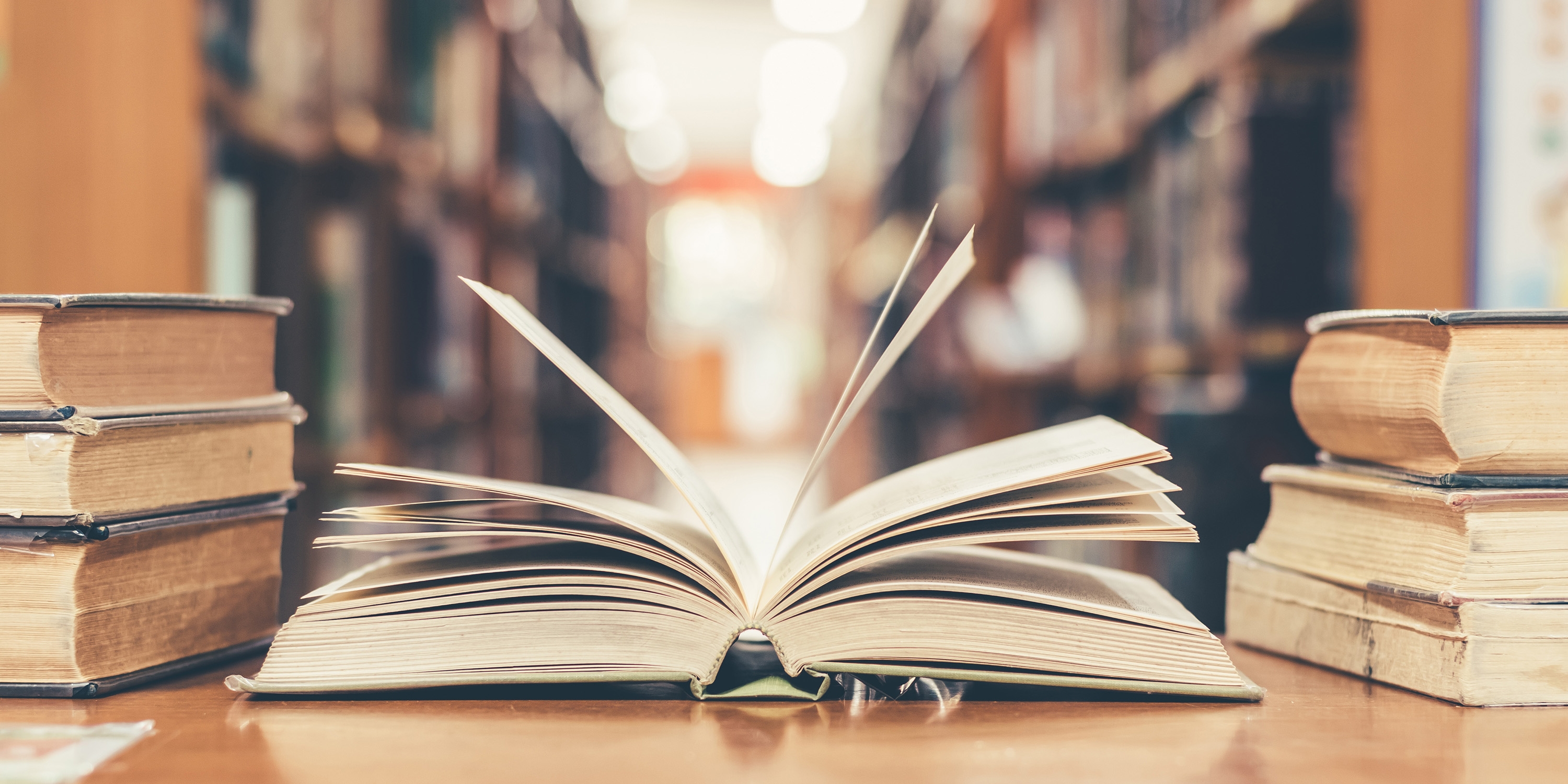 Book in library with old open textbook, stack piles of literatur
