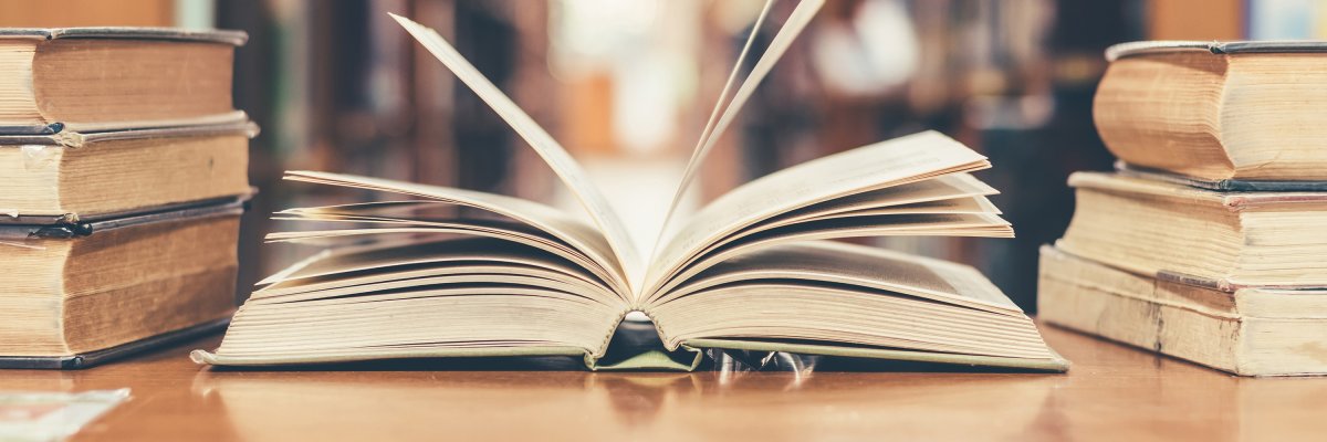 Book in library with old open textbook, stack piles of literatur Book in library with old open textbook, stack piles of literatur