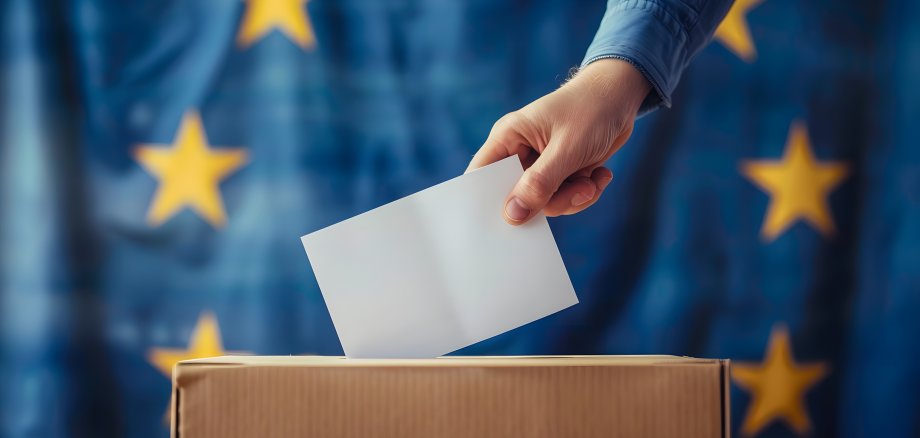 Person wirft Stimmzettel in eine Urne - Europawahl