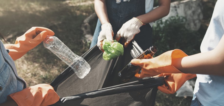 people picking up garbage and putting it in plastic black bag fo